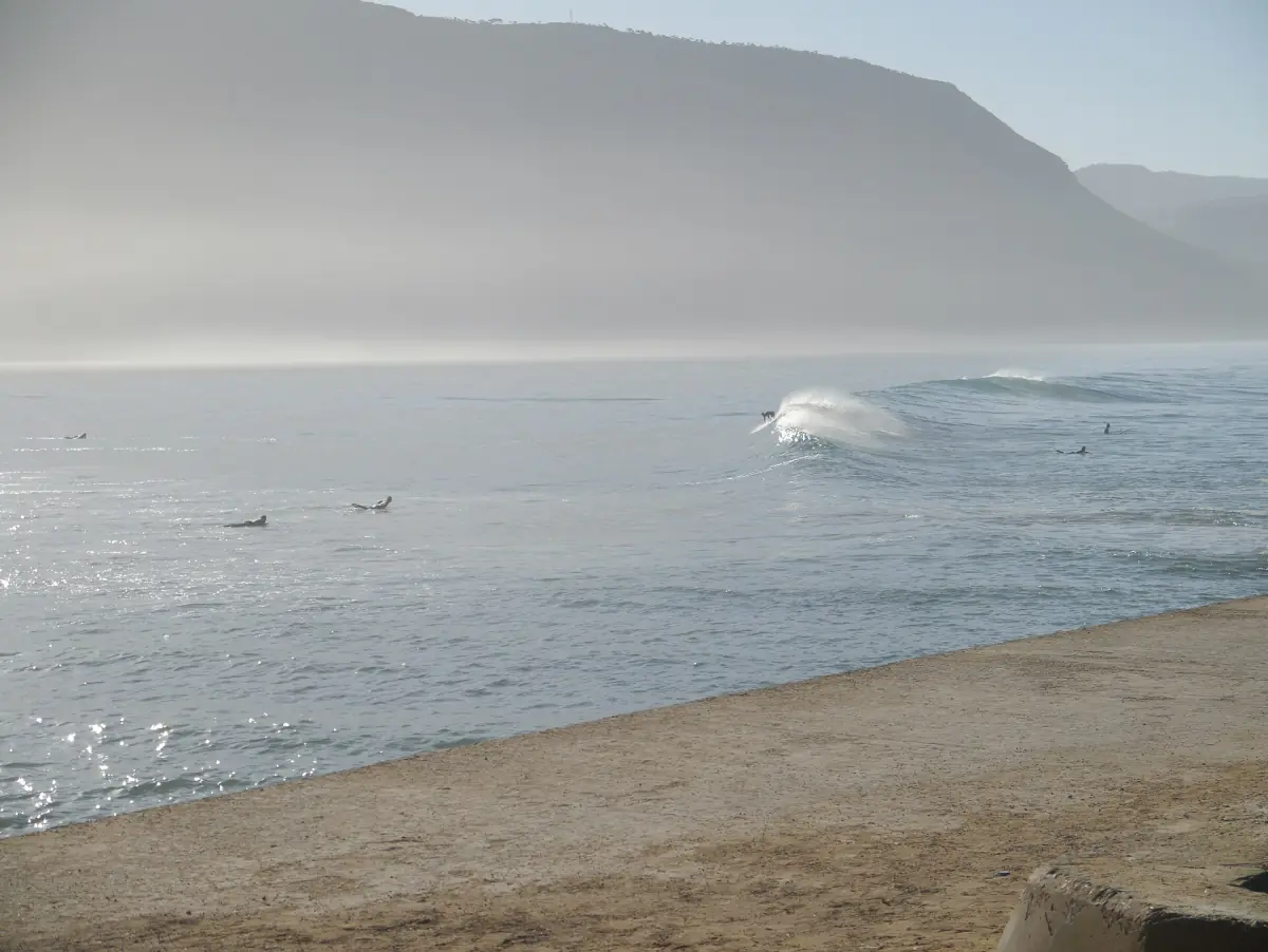 Wave breaking in a misty Atlantic bay below rugged coastal hills