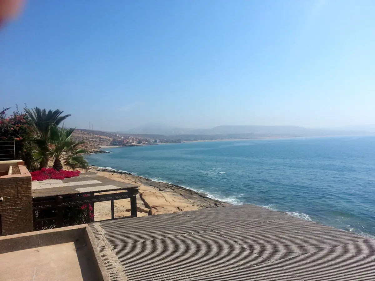 Terrace with flowers overlooking a long Atlantic coastline and calm blue sea