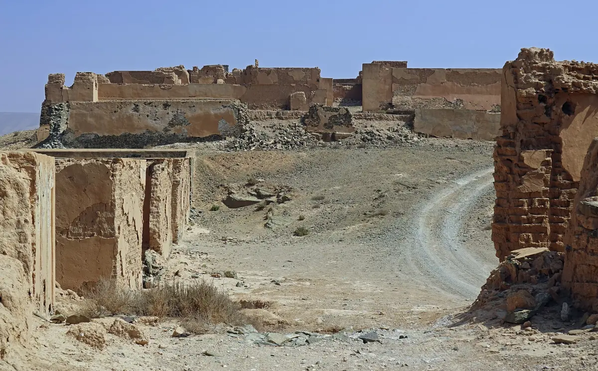 Ruined walls of Fort Bou Jerif with a dirt track through the dry landscape