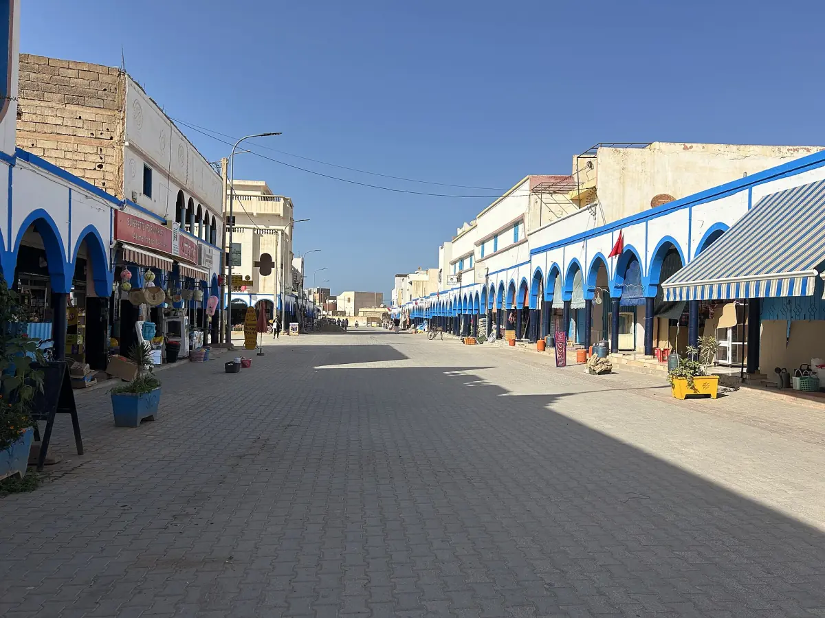 Blue and white arcade along a paved pedestrian street in the centre of Mirleft