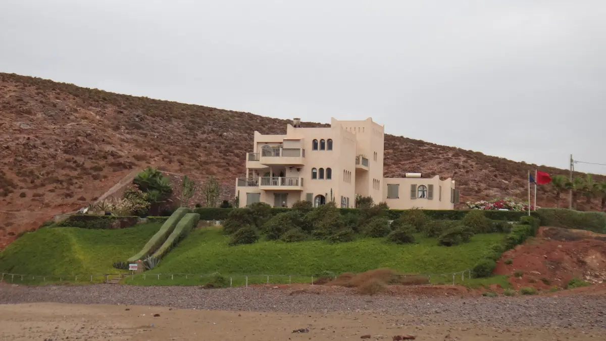 Modern beige holiday building with a green terraced lawn on a hillside near Mirleft