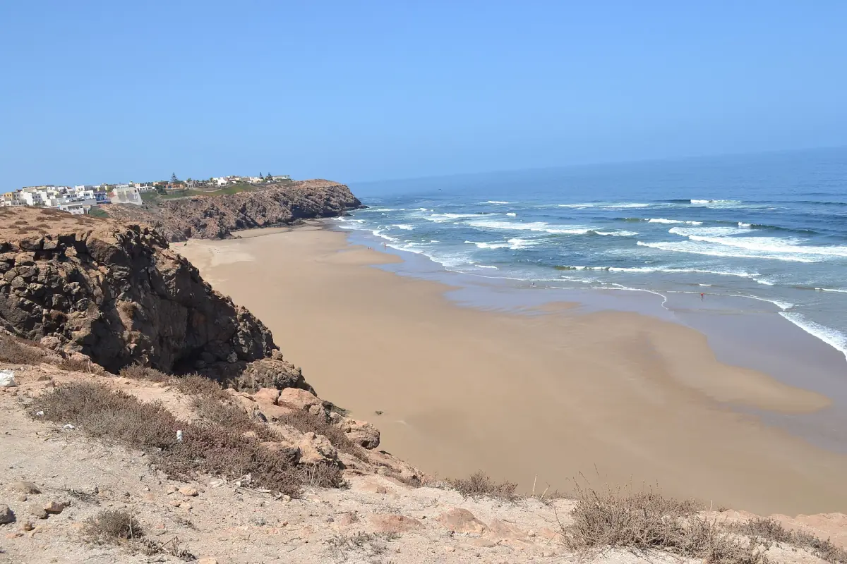 Sandy main beach of Mirleft seen from a rocky cliff with white houses beyond