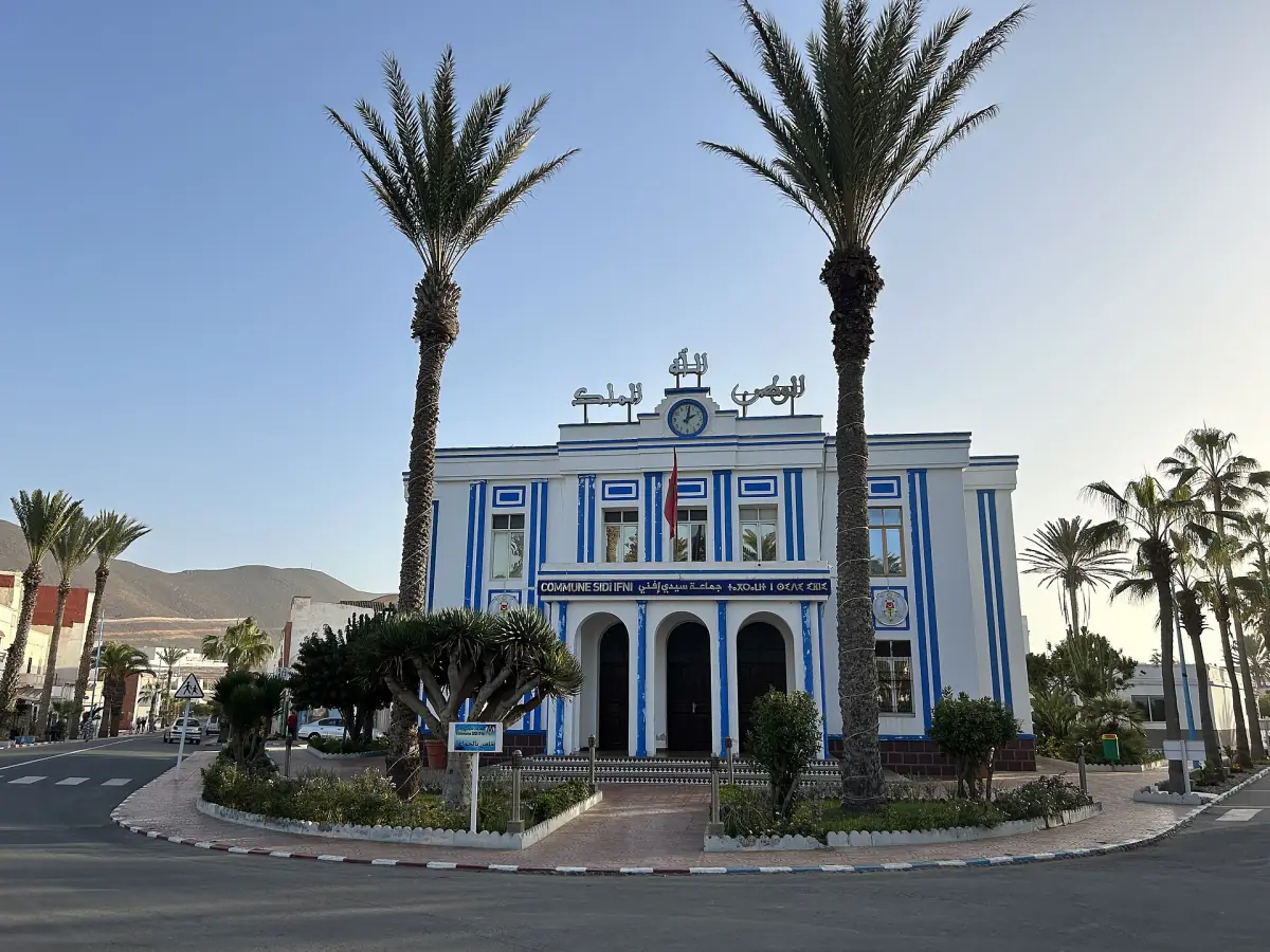 Blue and white town hall of Sidi Ifni framed by tall palm trees